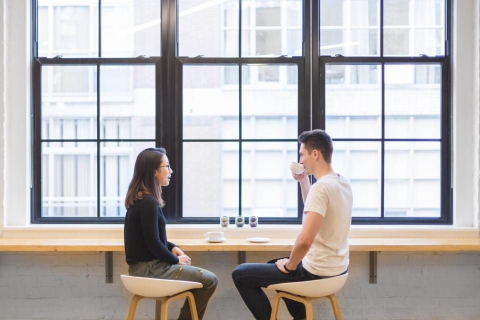 Dos personas conversando junto a una ventana
